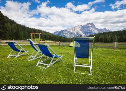Chairs on the green grass meadow with alpine mountain view
