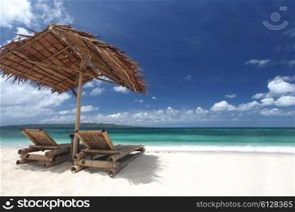 Chairs with parasol on beach. Relaxing couch chairs with straw parasol on white sandy beach at Philippines