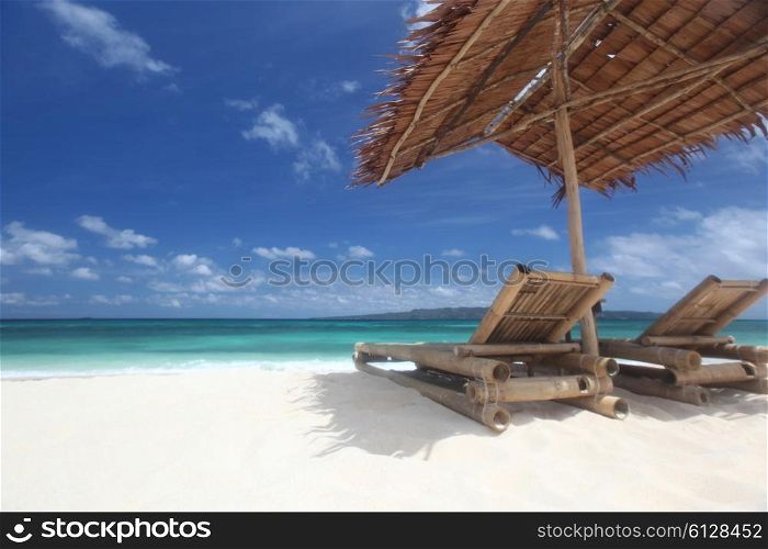 Chairs with parasol on beach. Relaxing couch chairs with straw parasol on white sandy beach at Philippines