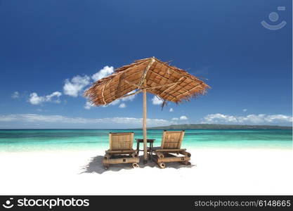 Chairs with parasol on beach. Relaxing couch chairs with straw parasol on white sandy beach at Philippines