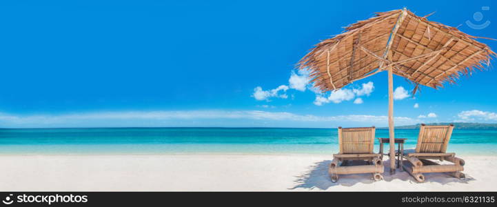 Chaise lounges on beach. Two chaise lounges and straw umbrella on tropical beach