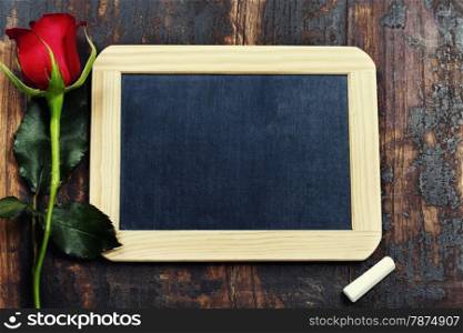 chalk board and rose on wooden background