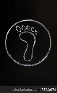 Chalk drawing of footprint symbol on a blackboard background with a circle