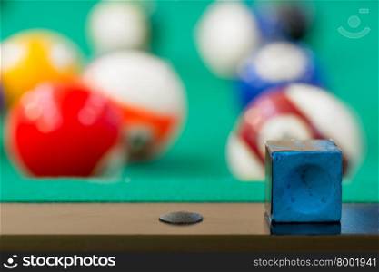 chalk for the cue is on the edge of the table for billiards