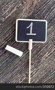 chalkboard, black with number 1, closeup on a wooden board. inscription chalk number