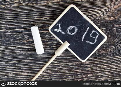 chalkboard, black with the year 2019, closeup on a wooden board. Label inscription chalk