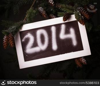 Chalkboard on the pine brach under the snow with 2014 new year