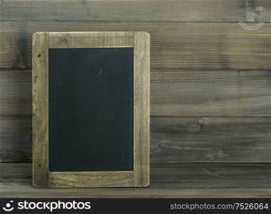 Chalkboard on wooden textured background. Vintage style toned picture