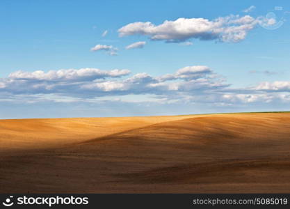 chalky plowed soil in a big field under a blue cloudy sky in springtime