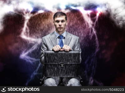 Challenge in business. Conceptual image of troubled businessman sitting under rain