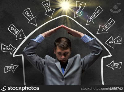 Challenge in business. Frustrated businessman protecting his head with arms