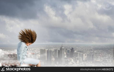 Challenge in business. Young businesswoman with waving hair sitting on top of building