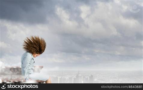 Challenge in business. Young businesswoman with waving hair sitting on top of building