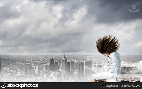 Challenge in business. Young businesswoman with waving hair sitting on top of building