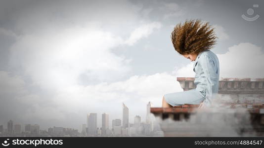 Challenge in business. Young businesswoman with waving hair sitting on top of building