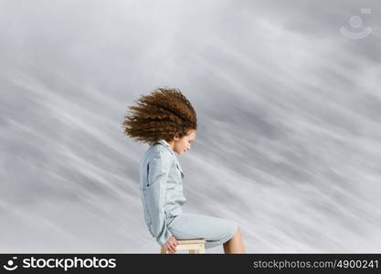 Challenge in business. Young businesswoman with waving hair sitting on top of building