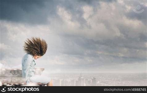 Challenge in business. Young businesswoman with waving hair sitting on top of building