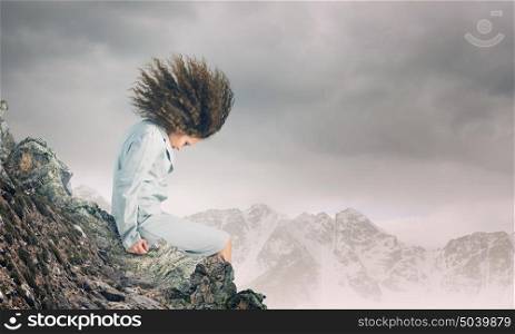 Challenge in business. Young businesswoman with waving hair sitting on top of mountain