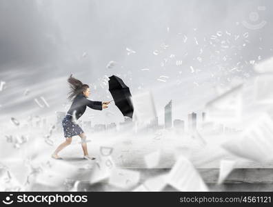 Challenge in business. Young determined businesswoman walking against strong wind