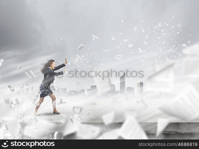 Challenge in business. Young determined businesswoman walking against strong wind