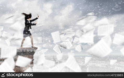 Challenge in business. Young determined businesswoman walking against strong wind