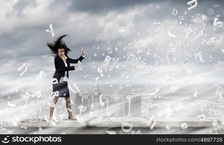 Challenge in business. Young determined businesswoman walking against strong wind