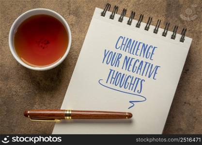 challenge your negative thoughts - inspirational advice or reminder - handwriting in a notebook with a cup of tea, positivity and personal development concept