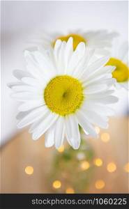Chamomile flowers in a vase on a wooden table. Flat lay, top view. Close-up.. Chamomile flowers in a vase on a wooden table. Flat lay, top view.