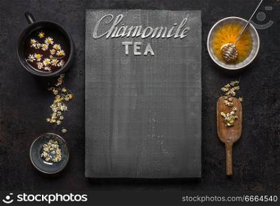 Chamomile tea background with cup of tea, dried chamomile flowers and honey in bowl, top view. Frame. Remedy to treat a wide range of health issues. Herbal medicine concept. Text lettering.