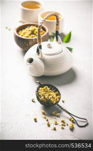 chamomile tea in strainer on vintage background - herbal tea and relaxation concept