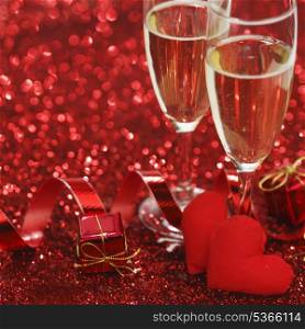 Champagne and valentines day gifts on red glitter background