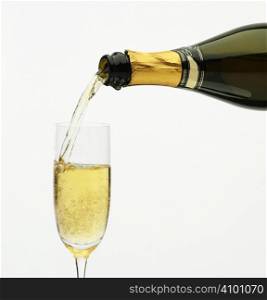 Champagne being poured into a flute, isolated on a white background.