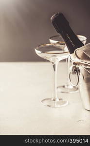 Champagne bottle in bucket and glasses on concrete background, copyspace. Champagne bottle in bucket and glasses on concrete background