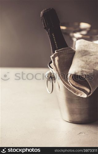Champagne bottle in bucket and glasses on concrete background, copyspace