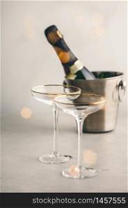 Champagne bottle in bucket with ice and glasses