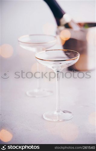 Champagne bottle in bucket with ice and glasses