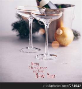 Champagne bottle in bucket with ice, glasses and Christmas decorations on concrete background