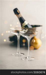 Champagne bottle in bucket with ice, glasses and Christmas decorations on concrete background
