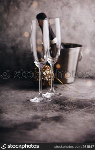 Champagne bottle in bucket with ice, glasses and Christmas decorations on grey stone background. Champagne bottle in bucket with ice, glasses and Christmas decorations