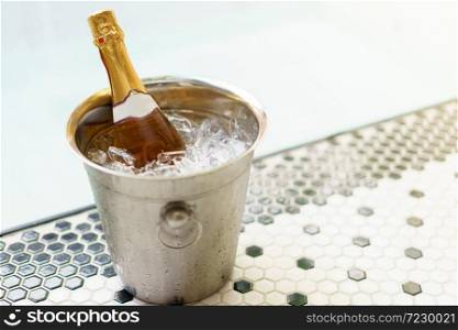 Champagne bottle in ice bucket and two glasses near bubble pool