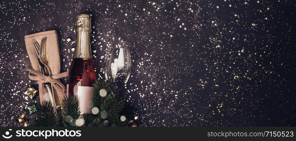 Champagne bottle with christmas decoration on dark background. Flat lay. Party concept.