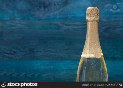 Champagne bottle with drops of water against a petrol-colored background.. Champagne bottle with drops of water against a petrol-colored background