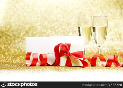 Champagne glasses and gift on glitters with white copy space