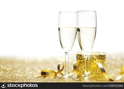 Champagne glasses and gift on glitters with white copy space