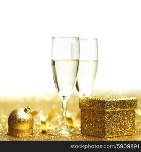 Champagne in glasses and gift box on golden background. Champagne and gift