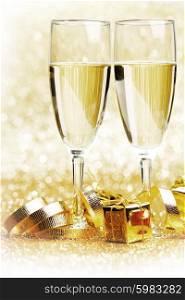 Champagne in glasses and gift boxes on golden background