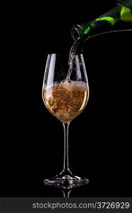Champagne pouring from bottle into a glass on black background