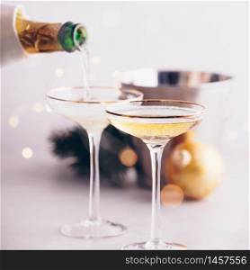 Champagne pouring into glasses and Christmas decorations on concrete background