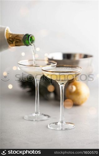 Champagne pouring into glasses and Christmas decorations on concrete background