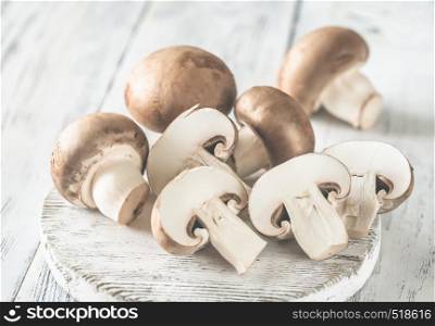 Champignon mushrooms - whole and halved ones- on the white wooden board